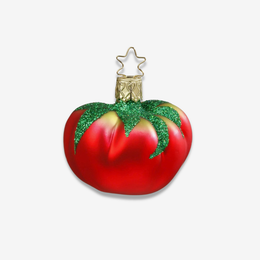 A red tomato-shaped Christmas ornament with glittery green leafy top and a gold star hanging loop, shown on a clean white background.