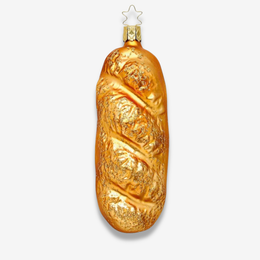 A decorative glass ornament shaped like a loaf of bread, finished in a shiny metallic gold color with textured scoring, topped with a gold cap and a small white star.