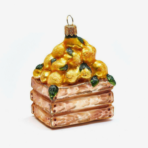 A decorative Christmas ornament shaped like a wood crate topped with golden-yellow lemons and green leaves, shown on a plain white background.