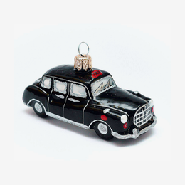 A black vintage "Cab" or Taxi car ornament from London UK with silver trim, white-tinted windows, small red accents, and a gold hanging loop on a plain white background.
