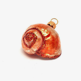 A spiral-shaped glass ornament resembling a seashell, decorated with shimmering orange glitter and a gold hanging loop, set against a plain white background.
