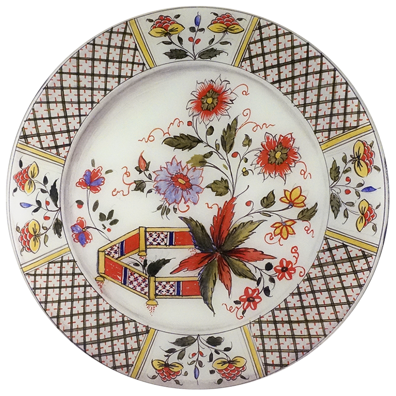 A 16-inch round glass plate featuring a red, yellow and blue flower drawing and a plaid pattern boarder. 