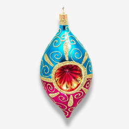 A decorative teardrop-shaped Christmas ornament with a glossy finish, featuring a blue top section with gold swirl patterns, a pink bottom section with gold swirl patterns, and a red and gold circular center design, hanging against a light gray background.