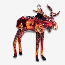 A moose-shaped decorative ornament with a glittery, textured finish in shades of red, orange, yellow, and black, featuring a gold hanging loop at the top, shown against a plain white background.