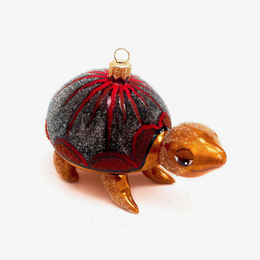 A decorative turtle ornament with a glittery dark gray shell accented by red patterns, a gold top loop, and a glittery gold head and legs, shown on a plain white background.