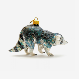 A hand-painted glass ornament shaped like a raccoon, featuring a textured black, white, and teal glaze with a gold hanging loop on a white background.