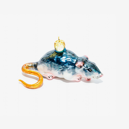 A handcrafted glass ornament shaped like a mouse, featuring a glossy blue and white body, pink inner ears and feet, a curled orange tail, and a small gold crown on its head, set against a plain white background.