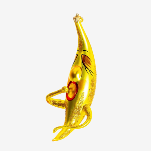 A whimsical, gold glitter Christmas ornament shaped like a moon with a painted face, eyes, and a red circular detail on its side, isolated on a white background.