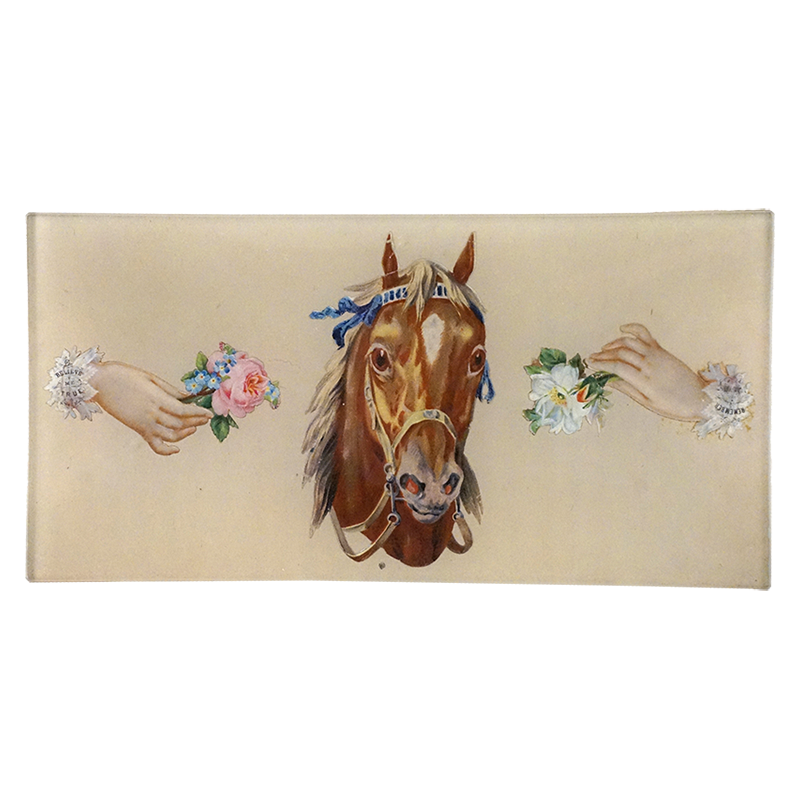 A brown horse head centered on a cream background, with two human hands reaching in from both sides and holding small flower bouquets on a four and a half by nine inch glass tray. 