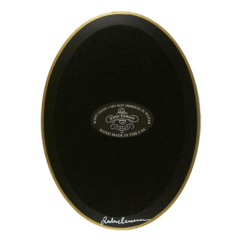 The back of a vertical 5 inch by 7 inch oval-shaped plate painted black with black felt backing and gold trim. Featuring the John Derian Company sticker and signed by John Derian. 