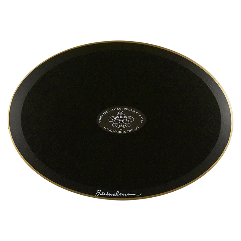 The back of a horizontal oval plate painted black with black felt backing and gold trim. Featuring the John Derian Company sticker and signed by John Derian. 