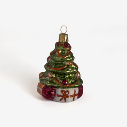 A small vintage-style Christmas tree ornament with a green glittery body, red and gold decorative accents, and wrapped gift details at the base, shown on a plain white background.
