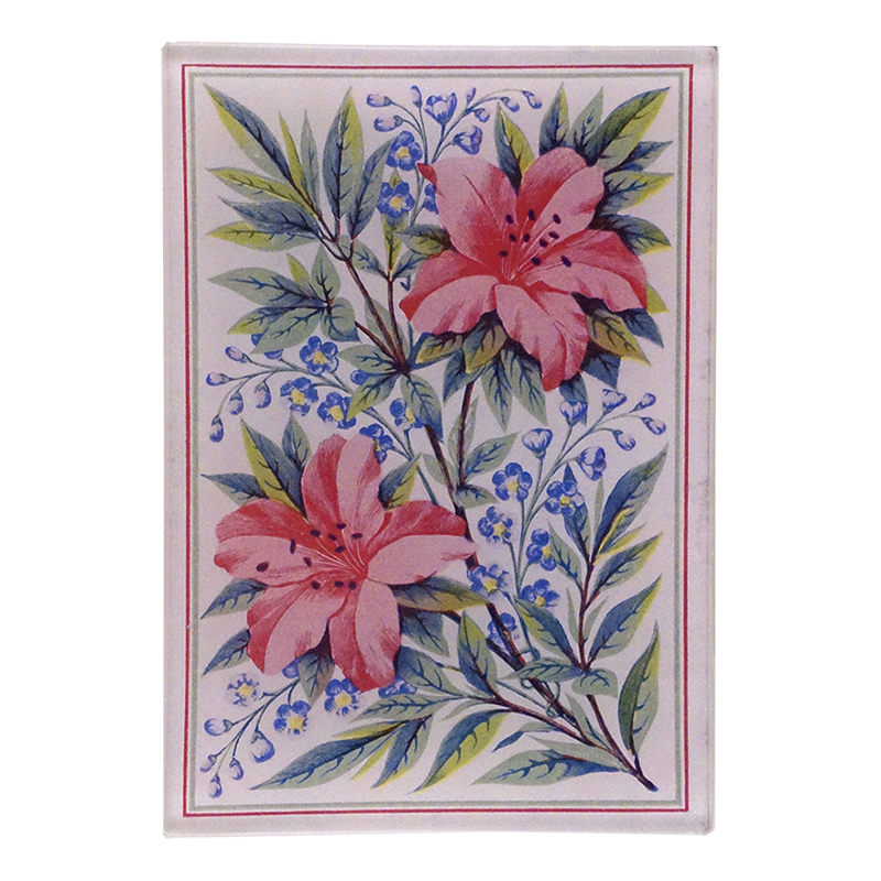 A vibrant floral pattern with a central image of two pink lily flowers surrounded by green leaves and a blue patterned border on a three and a half inch by five inch glass tray. 