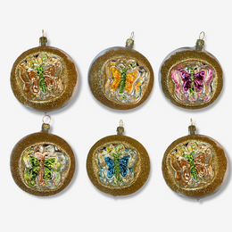 Set of six round gold glitter Christmas ornaments with embossed butterfly designs in various colors, arranged in two rows of three on a light gray background.