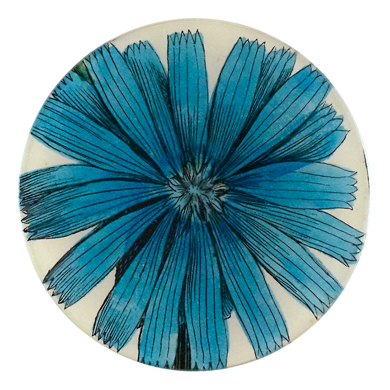 A five inch round glass plate with a handblown glass center featuring a collaged paper blue flower design.