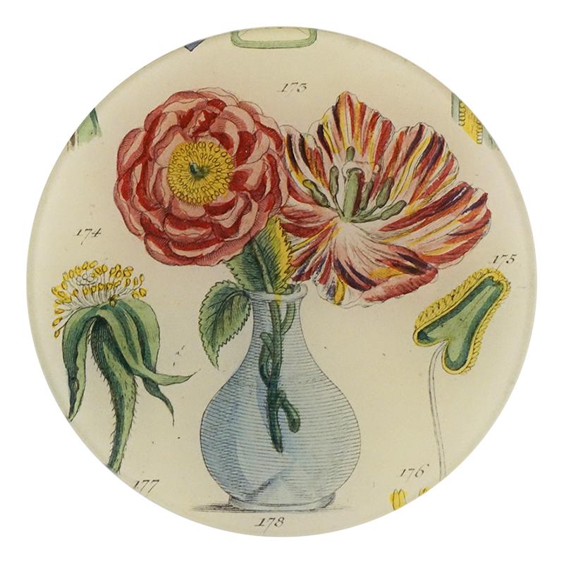 A five inch round glass plate featuring an illustration of two flowers in a vase surrounded by green and yellow foliage.  