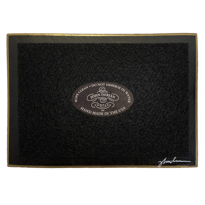 The back of a four and a half inch by six and a half inch tray that is painted black, with back felt, a gold trim and the John Derian Company logo sticker, signed by John Derian. 