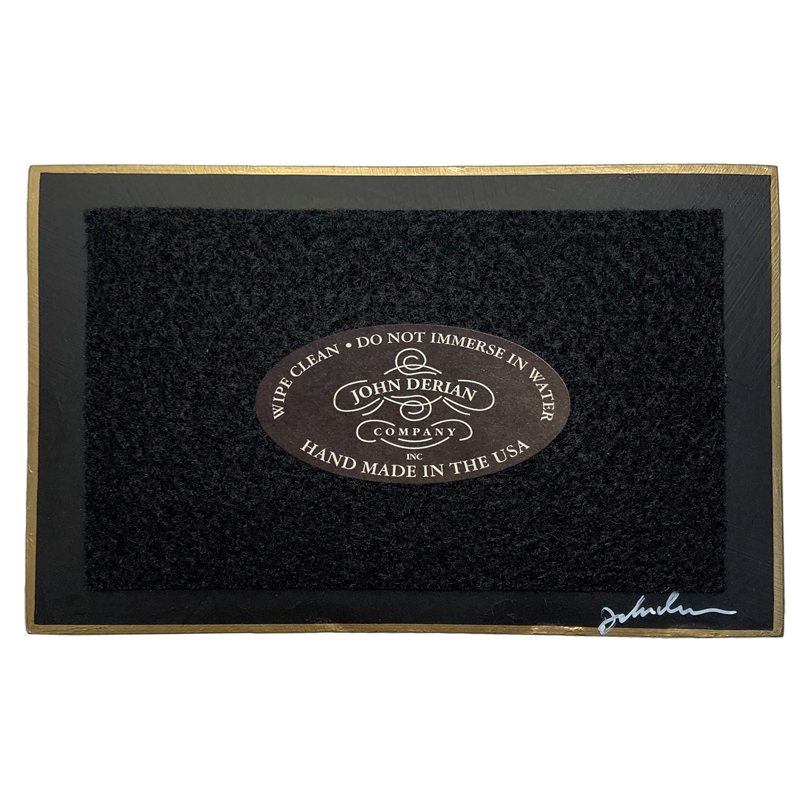 The back of a three and a half inch by five inch tray painted black with black felt and a painted gold boarder. Featuring the John Derian Company logo and sign signed by John Derian. 