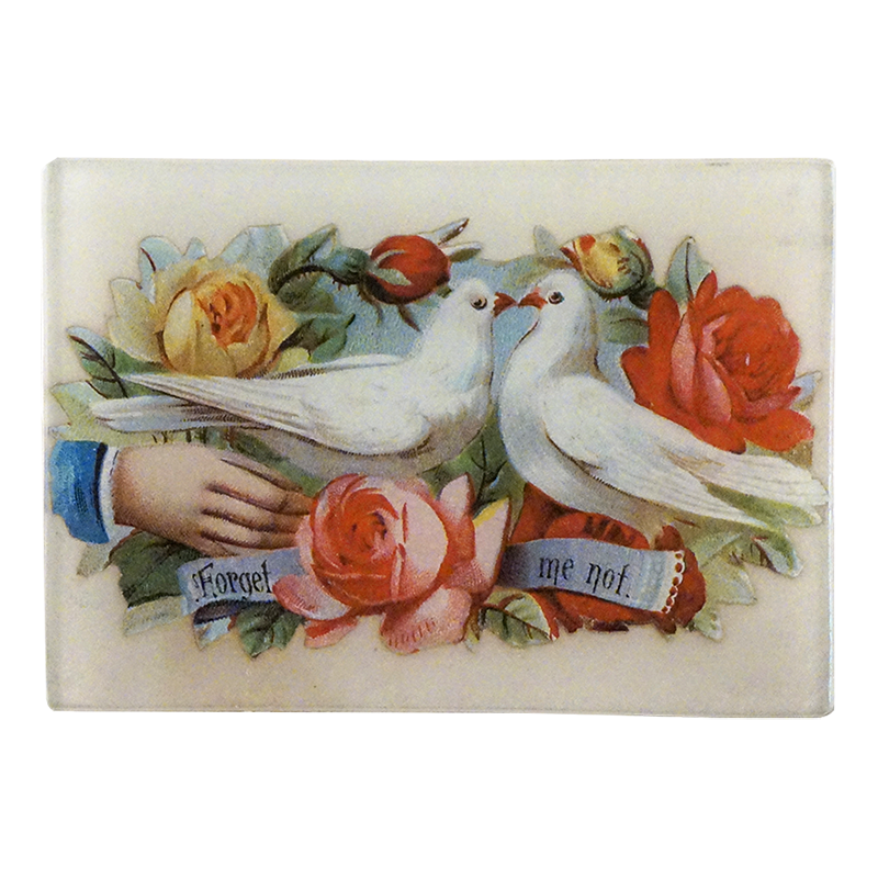 A glass tray featuring an artistic representation of two doves among various flowers with the text 'Forget me not' on it.