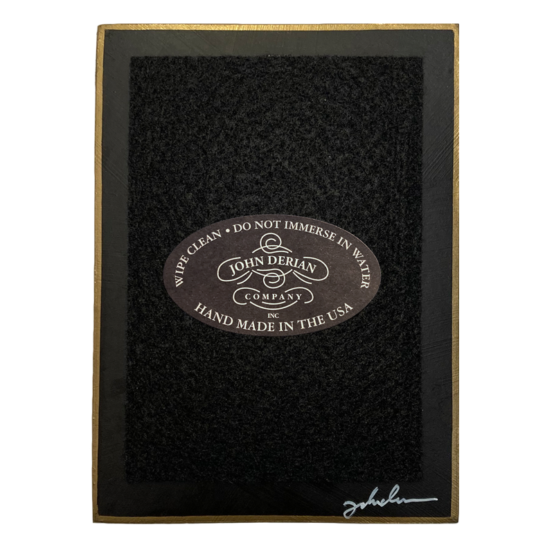 The back of a three and a half inch by five inch tray painted black with black felt and a painted gold boarder. Featuring the John Derian Company logo and sign signed by John Derian. 